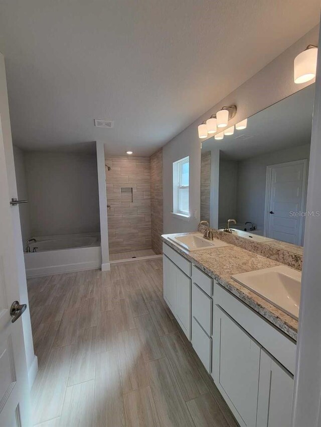 bathroom with hardwood / wood-style flooring, vanity, and plus walk in shower