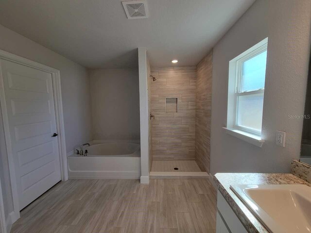 bathroom featuring vanity, separate shower and tub, and hardwood / wood-style floors