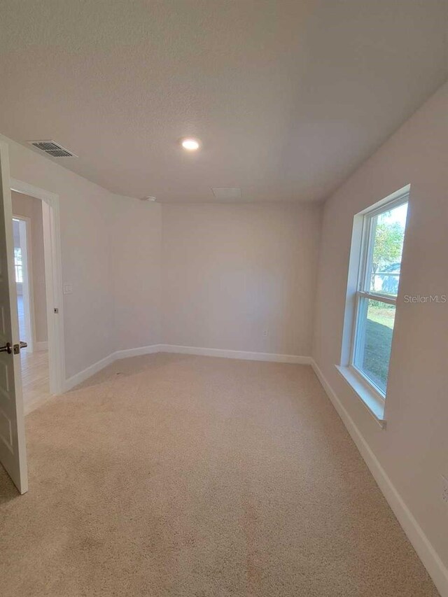 carpeted empty room with a textured ceiling