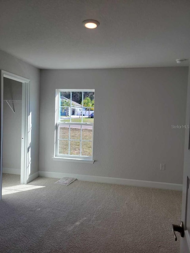 unfurnished bedroom featuring light carpet and a closet