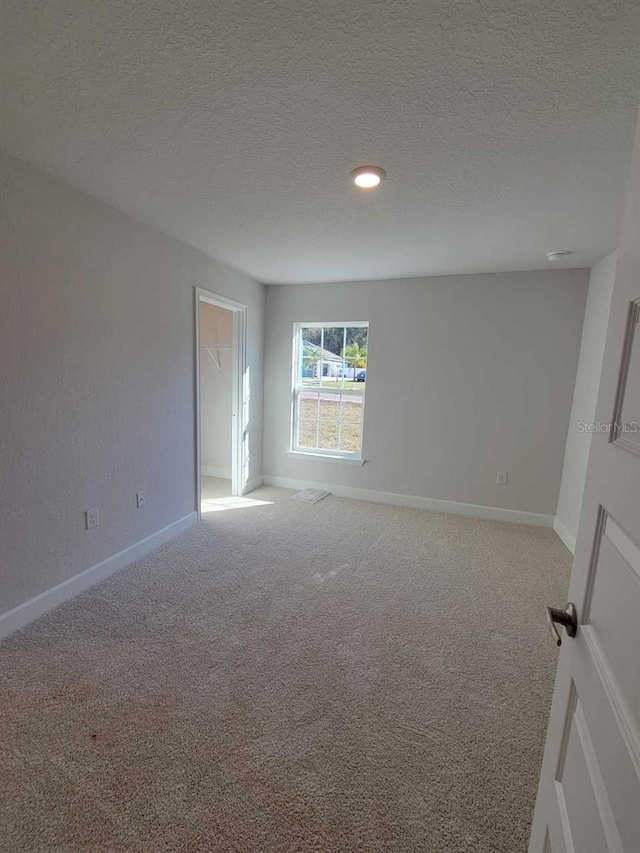 unfurnished room with light carpet and a textured ceiling