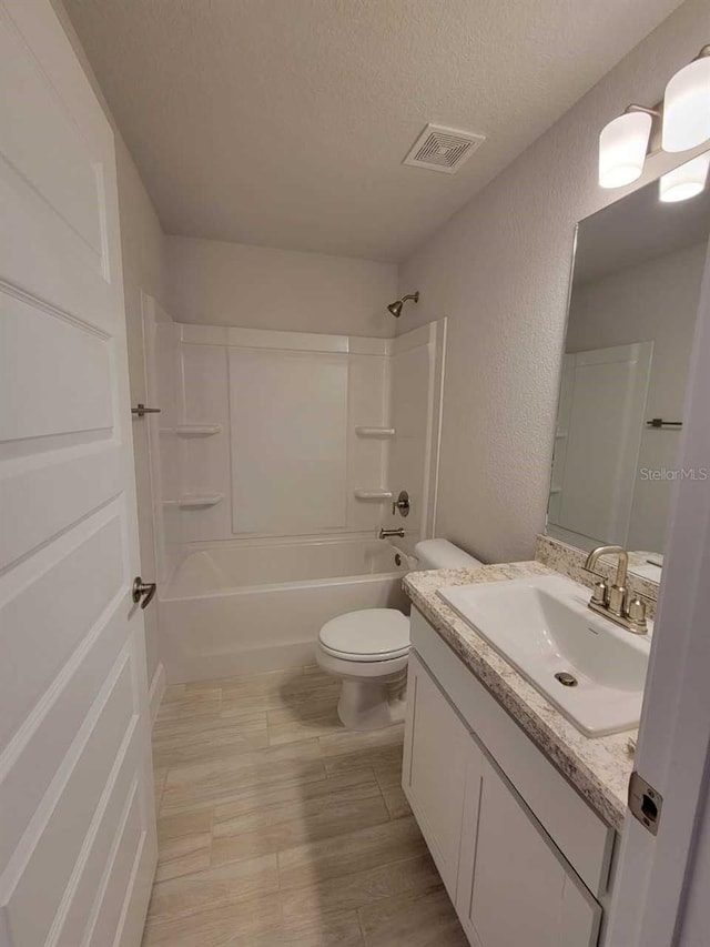 full bathroom featuring vanity,  shower combination, a textured ceiling, and toilet