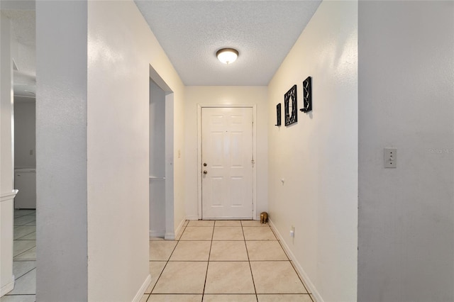 hallway with light tile patterned floors and a textured ceiling