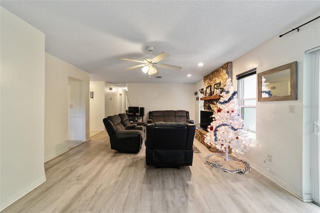 living room with a textured ceiling, light hardwood / wood-style floors, and ceiling fan