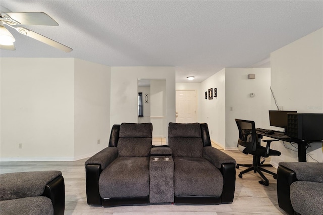 living room featuring a textured ceiling, light hardwood / wood-style flooring, and ceiling fan