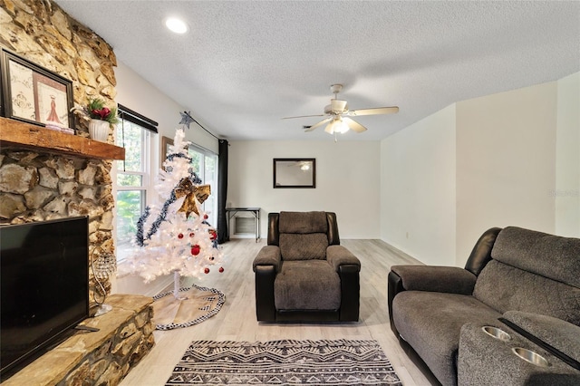 living room with a textured ceiling, light wood-type flooring, and ceiling fan