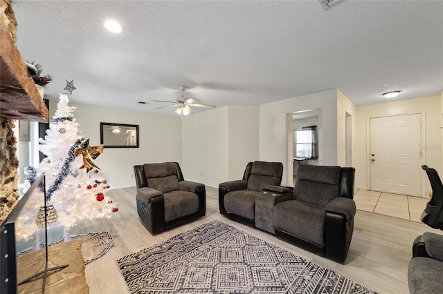 living room featuring ceiling fan, light hardwood / wood-style floors, and a textured ceiling