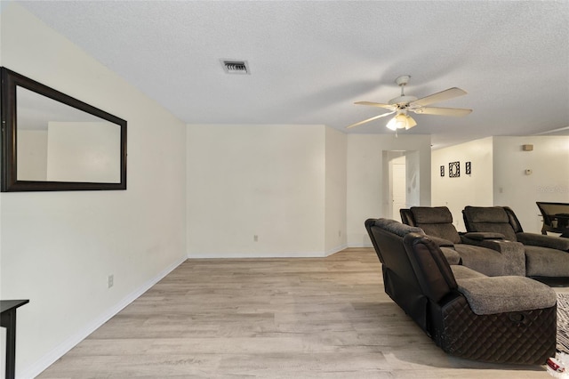 interior space featuring ceiling fan, a textured ceiling, and light hardwood / wood-style flooring