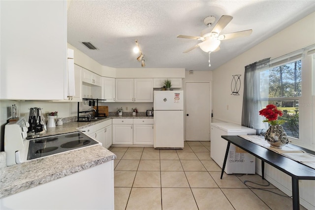 kitchen featuring white refrigerator, black stove, a textured ceiling, fridge, and white cabinetry