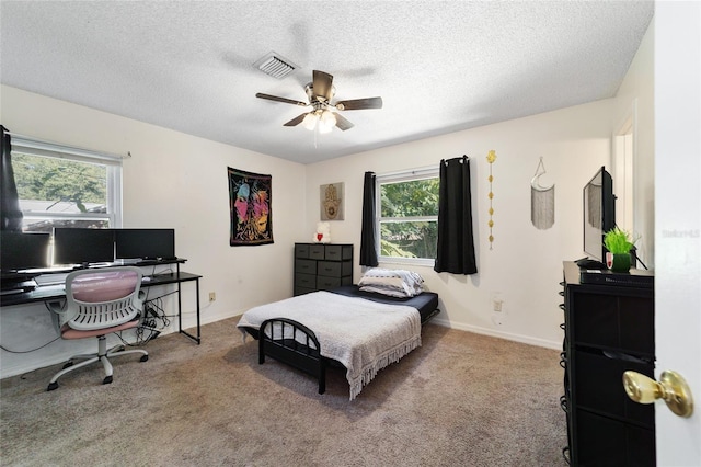 bedroom featuring ceiling fan, light colored carpet, a textured ceiling, and multiple windows