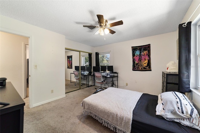 carpeted bedroom with ceiling fan, a closet, and a textured ceiling