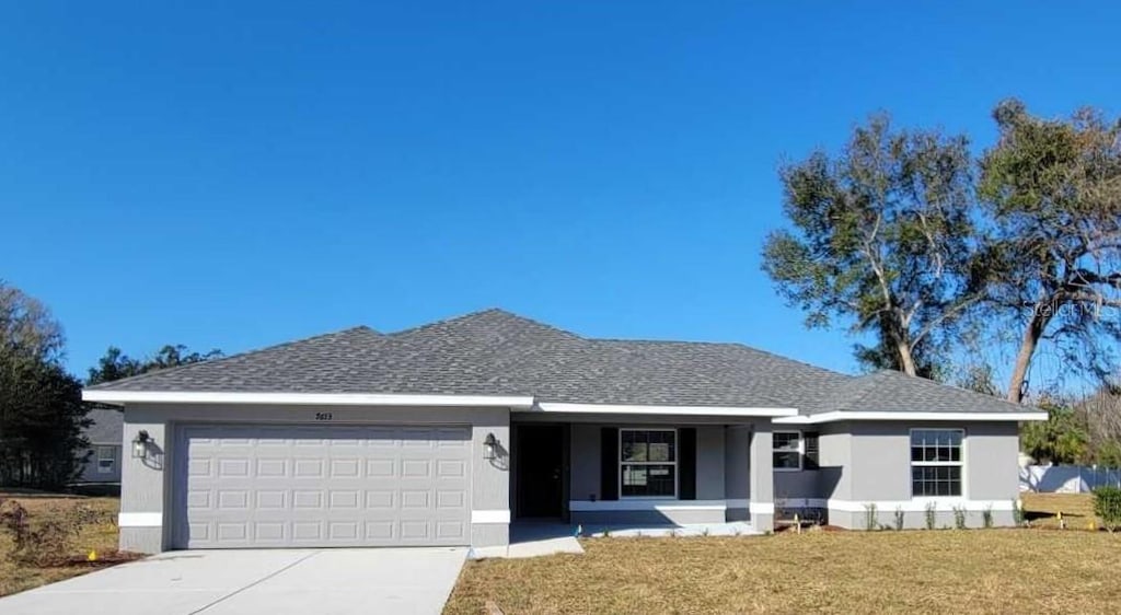 single story home with a garage and a front lawn