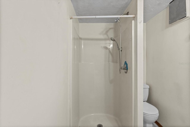 bathroom with a shower stall, toilet, and a textured ceiling