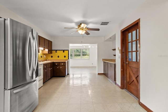 kitchen with white electric stove, dark brown cabinetry, visible vents, light countertops, and freestanding refrigerator