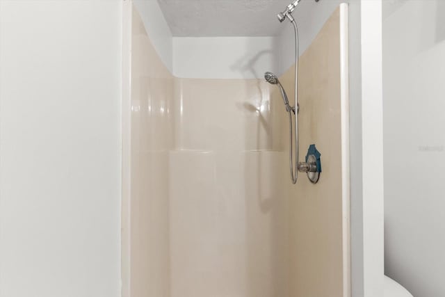 bathroom with toilet, walk in shower, and a textured ceiling