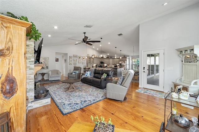 living room with a textured ceiling, light hardwood / wood-style floors, high vaulted ceiling, and ceiling fan