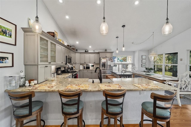 kitchen featuring gray cabinetry, a breakfast bar, vaulted ceiling, kitchen peninsula, and stainless steel appliances