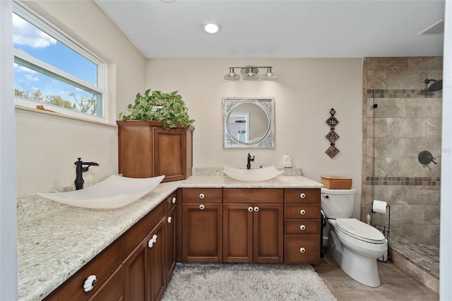 bathroom with tiled shower, vanity, toilet, and tile patterned flooring