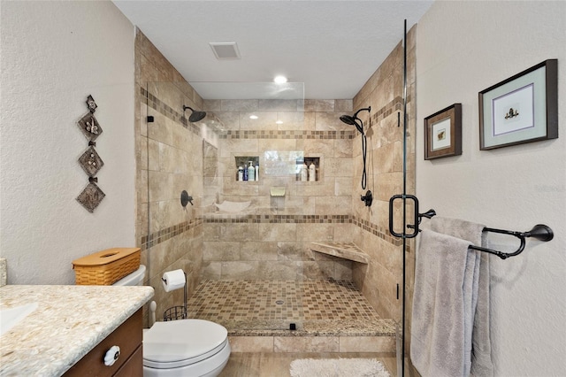 bathroom with vanity, toilet, an enclosed shower, and a textured ceiling