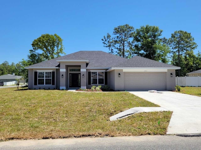 view of front facade featuring a front yard, stucco siding, driveway, an attached garage, and fence