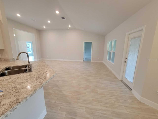 kitchen with recessed lighting, vaulted ceiling, a sink, baseboards, and visible vents