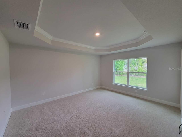 empty room featuring a raised ceiling, visible vents, baseboards, ornamental molding, and carpet floors