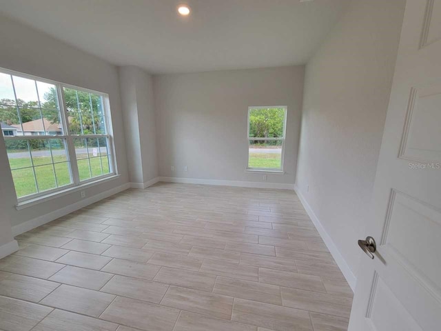 spare room featuring baseboards and light wood finished floors