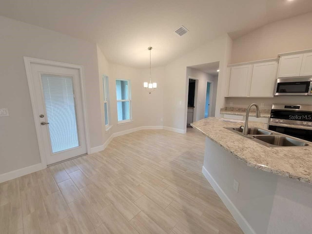 kitchen with white cabinetry, a sink, appliances with stainless steel finishes, a chandelier, and baseboards