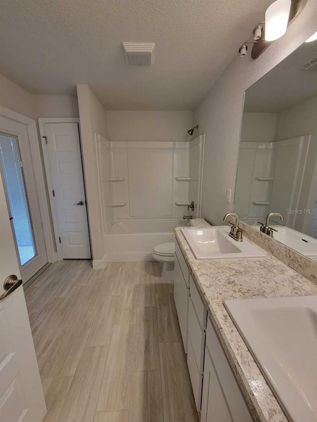 full bathroom featuring wood finished floors, a textured ceiling, shower / bath combination, and a sink