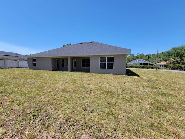 back of property featuring a lawn, stucco siding, and fence