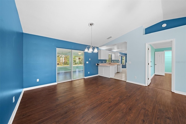 unfurnished living room with a notable chandelier, wood-type flooring, lofted ceiling, and sink