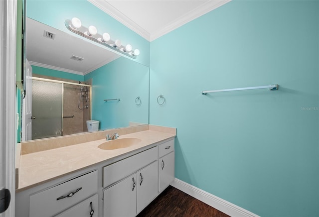 bathroom featuring hardwood / wood-style floors, vanity, a shower with door, toilet, and ornamental molding