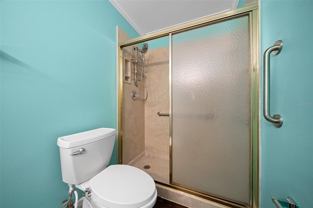 bathroom featuring toilet, a shower with shower door, and ornamental molding