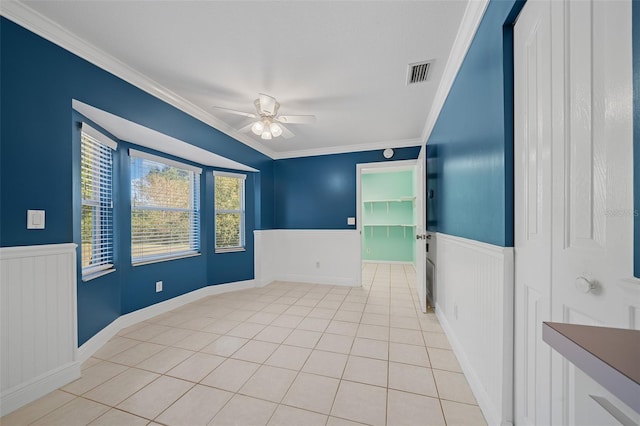 tiled empty room with ceiling fan and ornamental molding