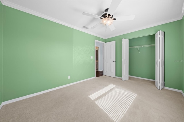 unfurnished bedroom featuring ceiling fan, a closet, crown molding, and light carpet