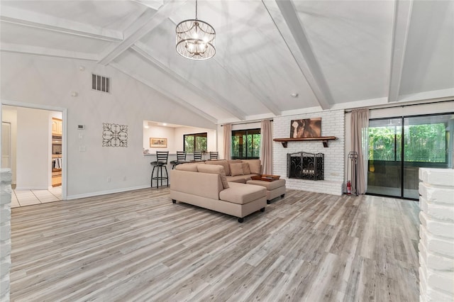 living room with a brick fireplace, high vaulted ceiling, light hardwood / wood-style flooring, beamed ceiling, and a chandelier