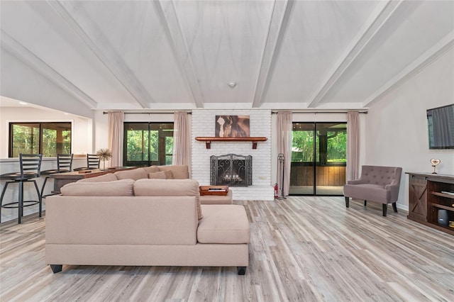 living room featuring a fireplace, beamed ceiling, a healthy amount of sunlight, and light hardwood / wood-style floors