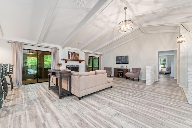 living room featuring light wood-type flooring, vaulted ceiling with beams, a fireplace, and a notable chandelier