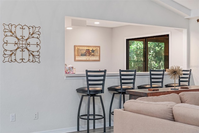 living room with vaulted ceiling with beams, indoor bar, and hardwood / wood-style flooring