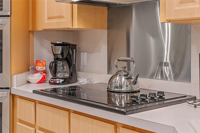 kitchen with black electric stovetop, light brown cabinets, oven, and stainless steel oven