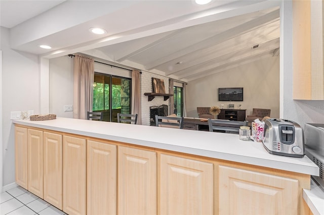 kitchen featuring kitchen peninsula, light brown cabinetry, lofted ceiling with beams, and light tile patterned floors