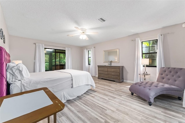 bedroom featuring ceiling fan, light hardwood / wood-style floors, and a textured ceiling