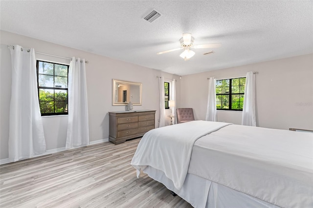 bedroom with ceiling fan, light hardwood / wood-style floors, and a textured ceiling