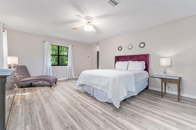 bedroom with ceiling fan, light hardwood / wood-style floors, and a textured ceiling