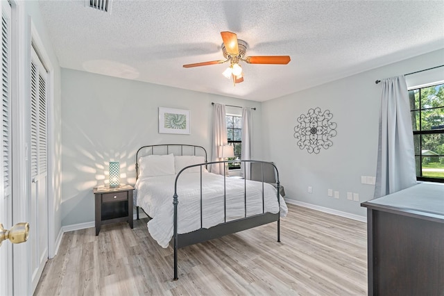 bedroom featuring ceiling fan, light hardwood / wood-style floors, a textured ceiling, and a closet