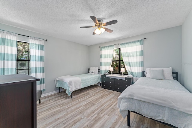 bedroom with ceiling fan, a textured ceiling, and light wood-type flooring