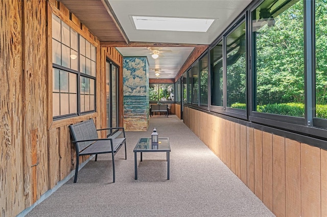 corridor with carpet flooring, wooden walls, and a skylight