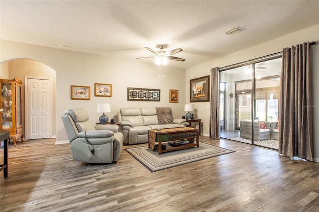 living room with ceiling fan, wood-type flooring, and a textured ceiling