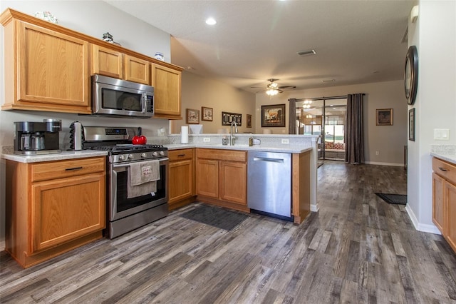 kitchen with kitchen peninsula, dark hardwood / wood-style flooring, stainless steel appliances, and ceiling fan