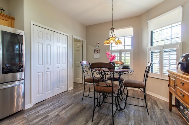 dining space featuring a wealth of natural light, dark wood-type flooring, and a notable chandelier